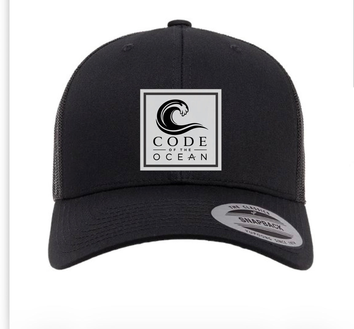Trucker hat in black with square Code of the Ocean logo